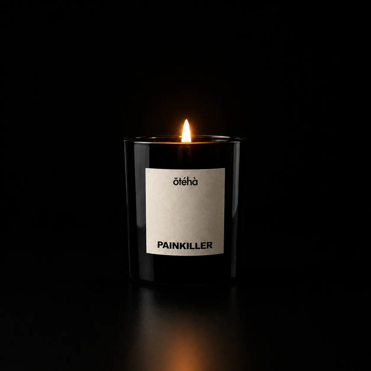 Painkiller leather scented candle by ōtéhà burning in a black glass vessel against a dark background