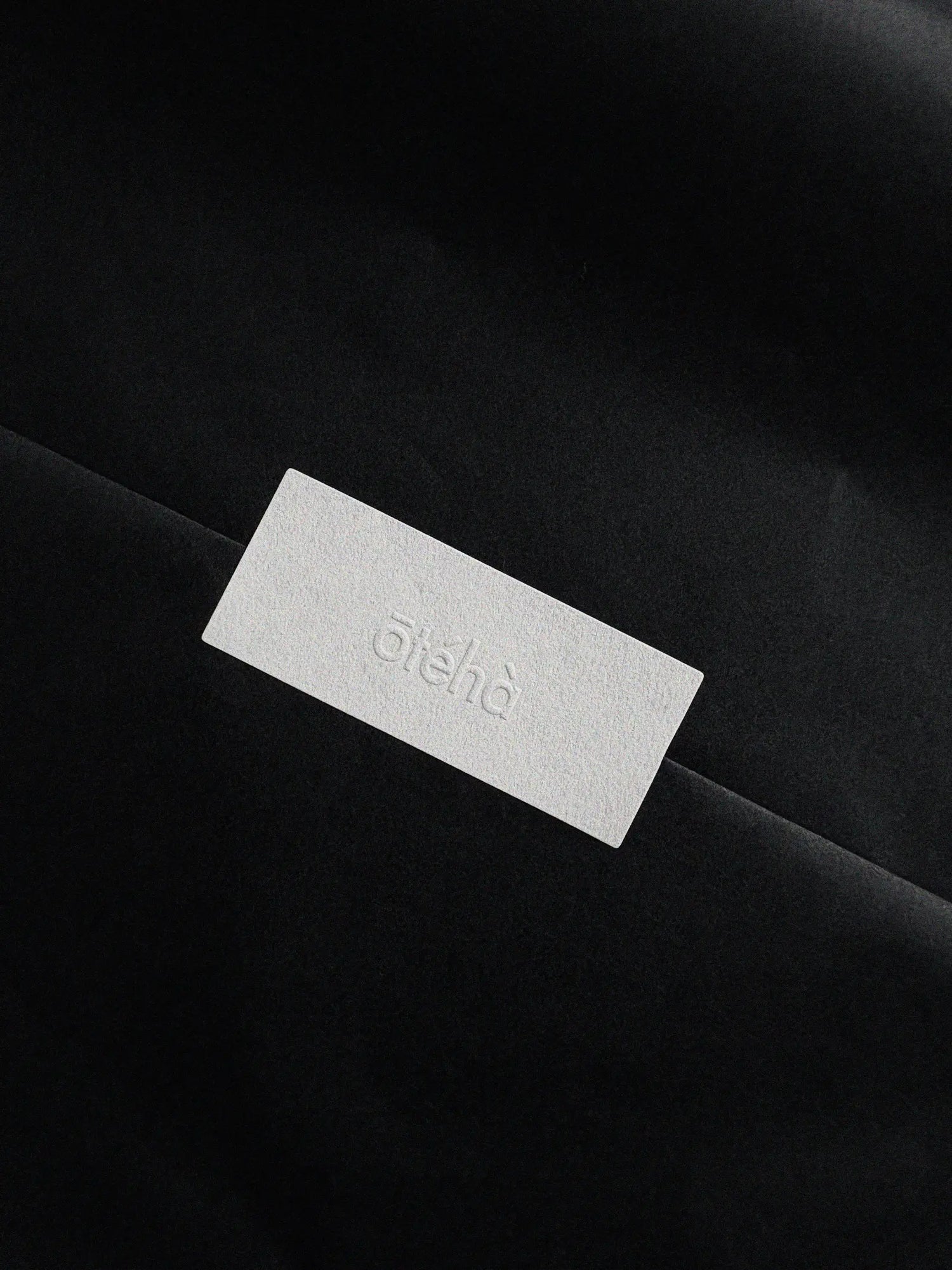 Embossed Ōtéhà logo on textured paper packaging detail